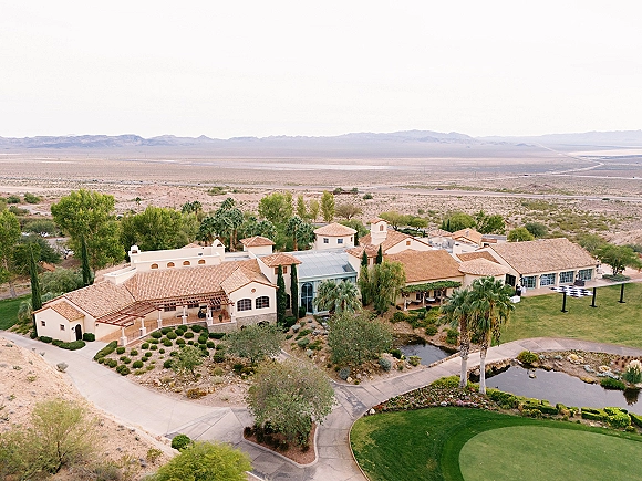 Wedding venue exterior with aerial wedding venue view, terracotta roofs, pergola patio, palm trees and pond, with mountains beyond the lawn