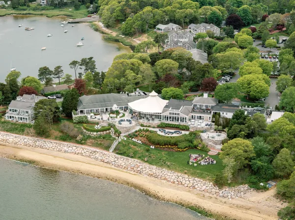 Waterfront wedding venue set for a coastal lawn ceremony with ceremony chairs, beside a beach shoreline and boats on the bay.