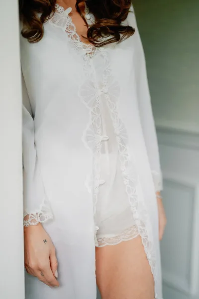 Bridal robe as a bride getting ready outfit, softly draped with delicate lace trim, capturing a quiet, intimate wedding morning mood.