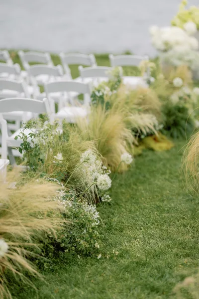 Ceremony aisle design for an outdoor ceremony aisle, edged with ornamental grasses on a grass lawn by the water.