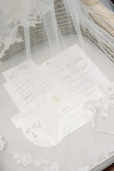 wedding invitation suite with RSVP card design styled in a wicker basket, accented by a delicate bridal veil on linen fabric.