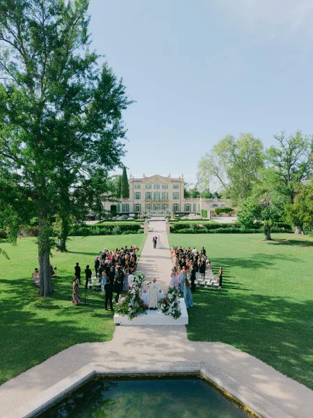 Ceremony moment as the couple begin their wedding recessional down a long aisle with elegant aisle arrangements, framed by a mansion facade.