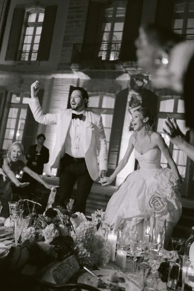 Reception moment with a couple dancing at reception, candles around them, set before a building facade with shuttered windows and steps.