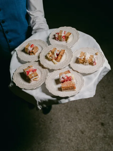 Wedding cake slices presented as plated wedding cake, each topped with strawberries, ready to be served.