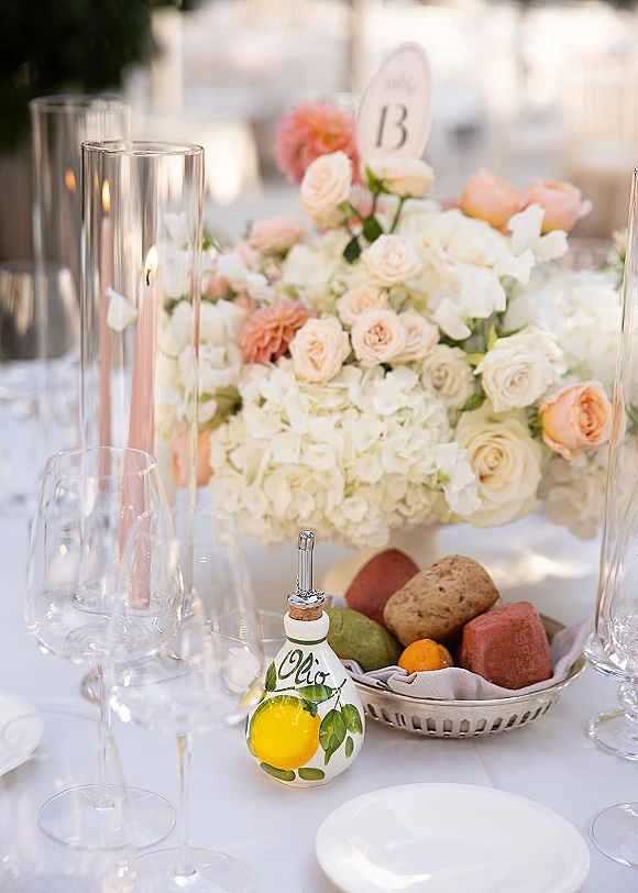 Reception tablescape with wedding table centerpiece of peach and ivory roses and hydrangeas, candlelit place settings on white linens