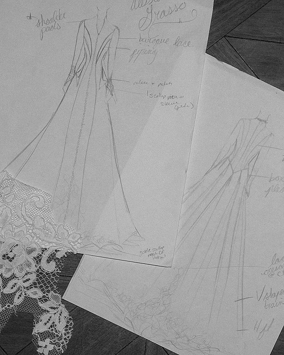 Wedding dress sketch with bridal gown design sketch details, lace applique accents on paper sheets spread across a wood table