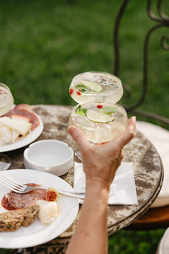 Wedding cocktails served as a signature wedding drink with lime and mint garnish beside charcuterie on a metal bistro table outdoors