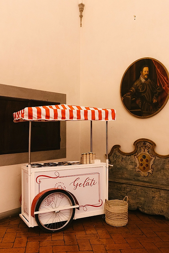 Gelato cart wedding gelato cart with red-and-white striped canopy, bicycle wheel, gelato tubs, waffle cups, and wicker basket indoors