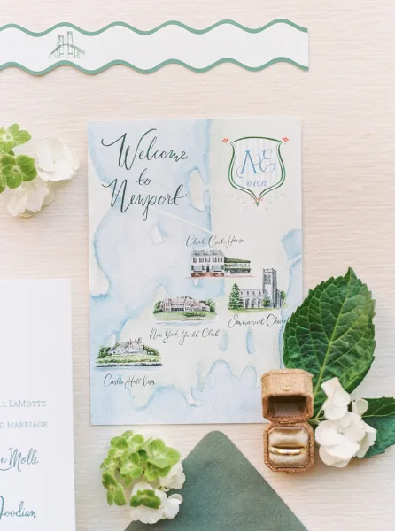 Wedding invitation suite with watercolor map invitation, calligraphy cards, wax-sealed envelope, rings and hydrangea on linen backdrop