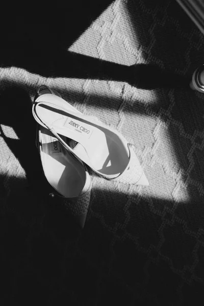 Wedding shoes, white slingback bridal heels with pointed toes and woven heel texture on patterned carpet in window light shadows