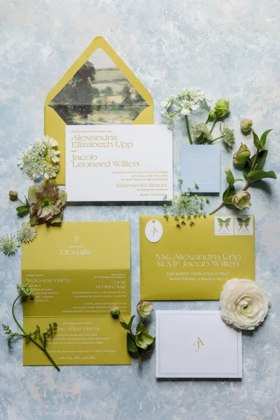 Wedding invitation suite featuring olive green wedding invitations and a matching envelope liner, arranged on a blue textured surface.