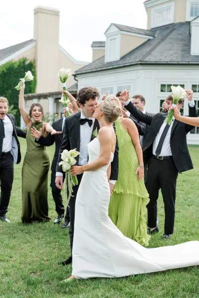 Wedding kiss portrait of newlyweds with wedding party, with a calla lily bouquet carried by the bride.