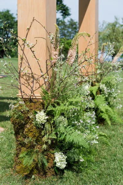 Ceremony flowers arranged as a grounded floral installation with ferns, forming lush meadow-style clusters along the altar.