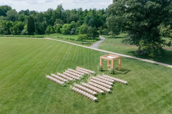 Outdoor ceremony setup with a clean ceremony seating layout facing a wooden canopy, styled in a minimalist, contemporary design.