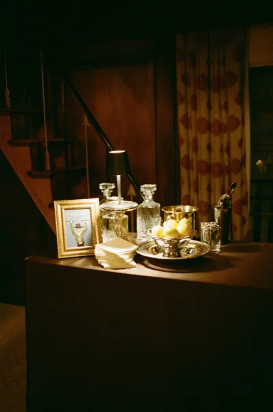 Cocktail bar setup styled as a signature cocktail station with crystal decanters, set against wood paneling and a staircase.