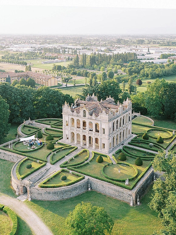 Wedding venue aerial view of a villa wedding venue with formal gardens, manicured hedges, stone terrace, and canopy lounge seating