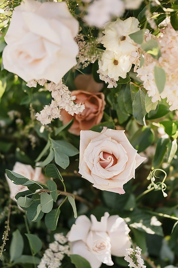Wedding flowers in a blush rose bouquet with white blooms and eucalyptus accents, shown close up against lush garden greenery