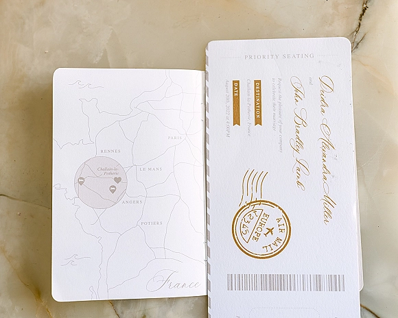 Wedding invitation suite with passport wedding invitation details in foil calligraphy, plus boarding pass card and map insert on marble surface