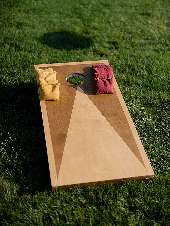 Wedding lawn games set up on a grass lawn, featuring a wedding cornhole board with bean bags ready for guests to play outdoors