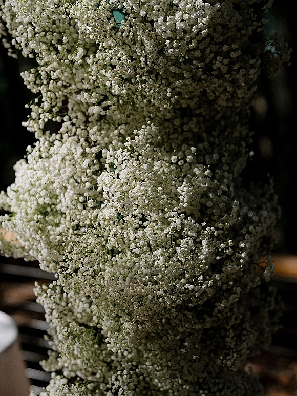 Baby's breath decor in a baby's breath wedding decor installation, forming a soft white floral column against a dark interior with furniture