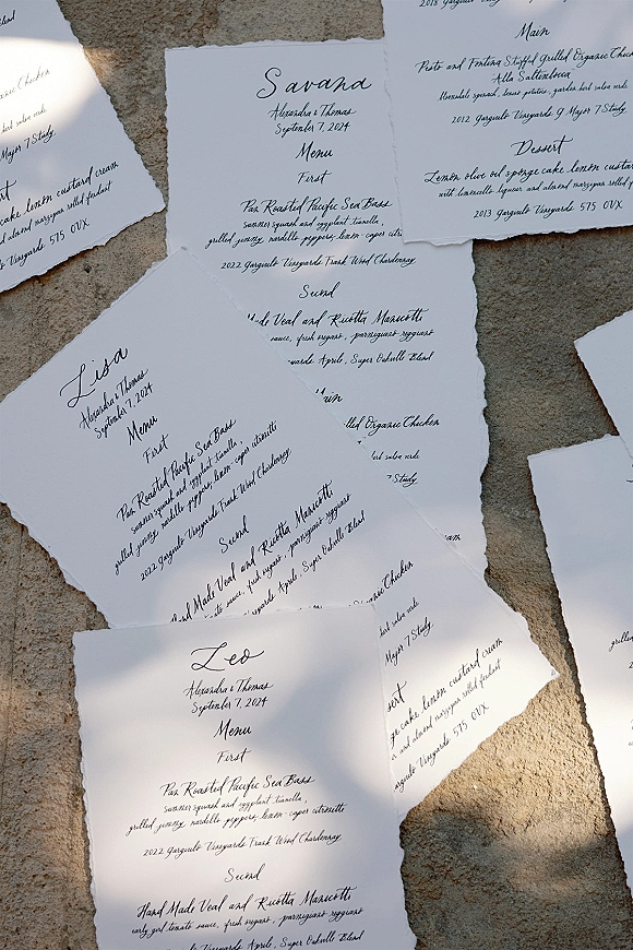 Wedding menu cards with calligraphy wedding menu lettering on deckle edge paper, laid on a stone surface with natural light shadows