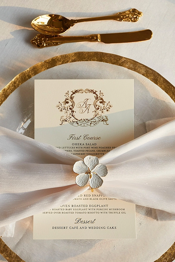 Wedding menu card with wedding menu design on a gold charger plate, set on a white napkin with a floral napkin ring on white tablecloth