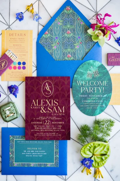 Wedding invitation suite with art deco wedding invitations, blue envelope and patterned liner, rings and orchid bloom on white marble flat lay