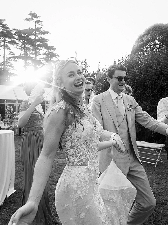 Wedding reception dancing as bride and groom in sunglasses laugh and move on a garden lawn near cocktail tables and an outdoor tent