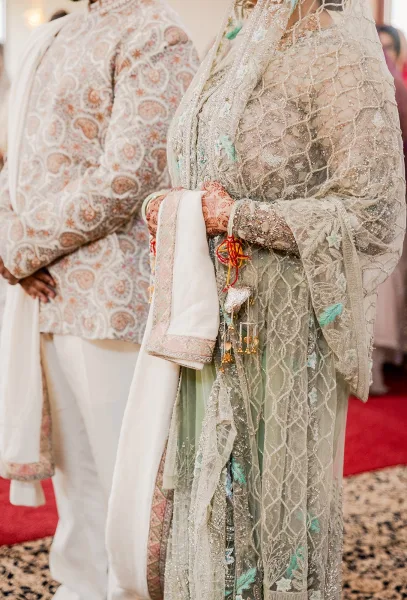 Bridal outfit with pakistani bridal dress details, mint green embroidery, sheer dupatta, henna hands and bangles on a red carpet aisle