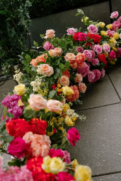 ceremony aisle flowers forming a grounded floral aisle, lush low clusters of roses on stone pavers beside an ivy-lined planter