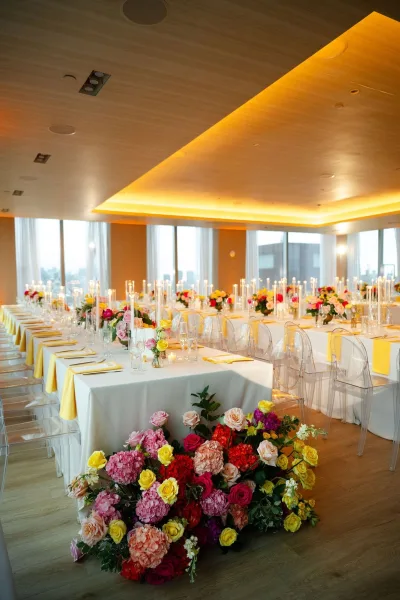 Reception tablescape with modern reception decor and taper candles, set before floor-to-ceiling windows framing the city skyline.