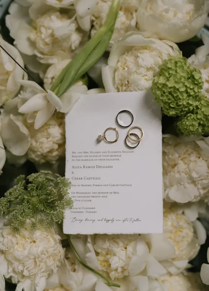 Invitation suite wedding invitation flat lay with letterpress cards, wedding rings, and white peonies and tulips in a floral arrangement backdrop