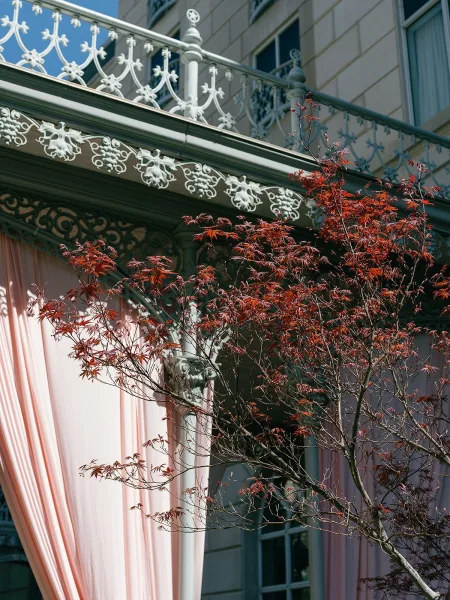 Wedding draping featuring blush pink draping sweeps along a wrought iron railing on a historic building facade.