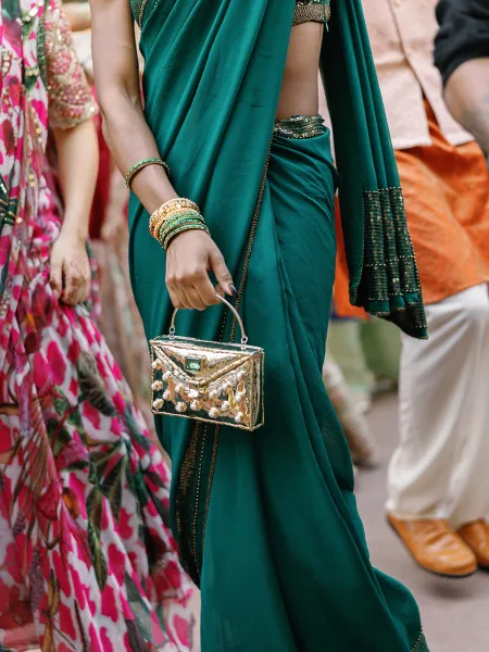 Wedding guest outfit in Indian wedding guest style, a green saree draped elegantly amid guests along a floral walkway.