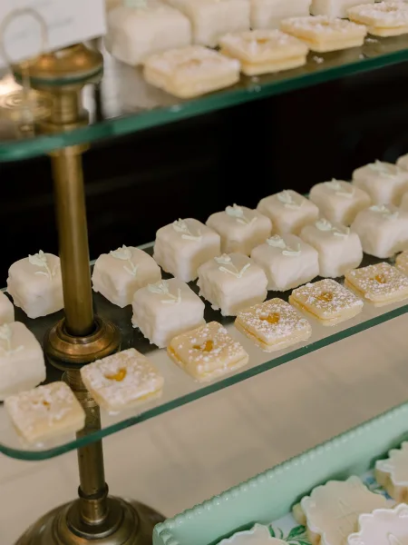 Petit fours arranged on a wedding dessert bar, neatly displayed on a brass stand to tempt guests with dainty, bite-size elegance.