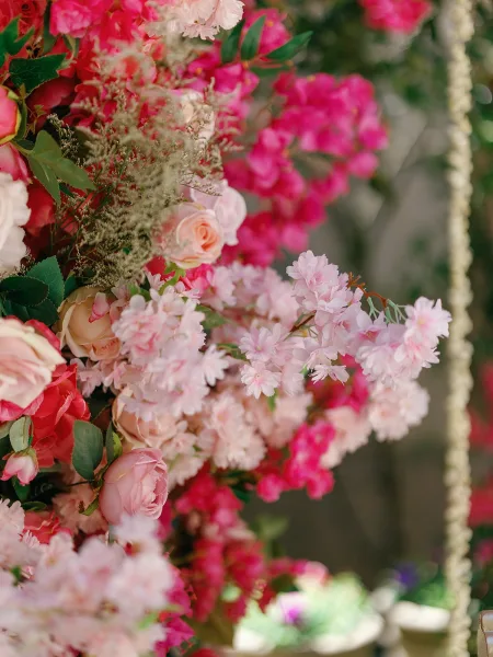 Wedding floral installation with pink garden roses and blossoming branches, a lush statement piece against softly blurred garden foliage.