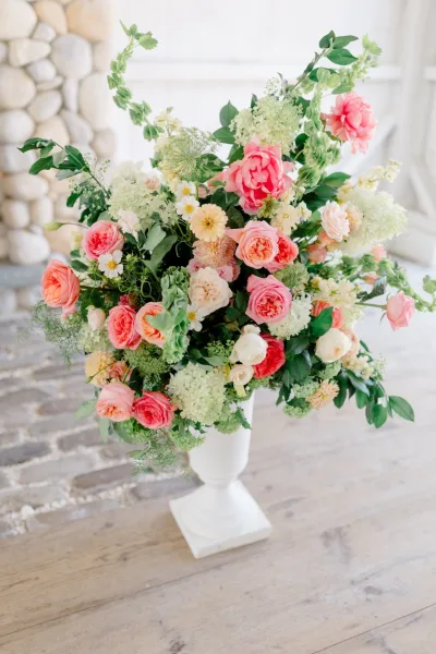 Wedding flower arrangement of lush mixed blooms in an urn vase, creating a romantic focal point and elegant display.