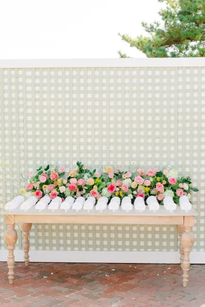 Wedding towel station and guest towel display with a floral arrangement, set against a lattice wall on a brick patio
