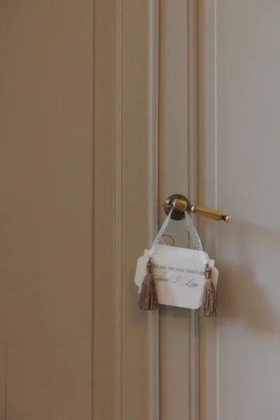 Wedding door hanger do not disturb wedding sign with calligraphy lettering and lace ribbon tassels on a painted paneled door by a brass handle