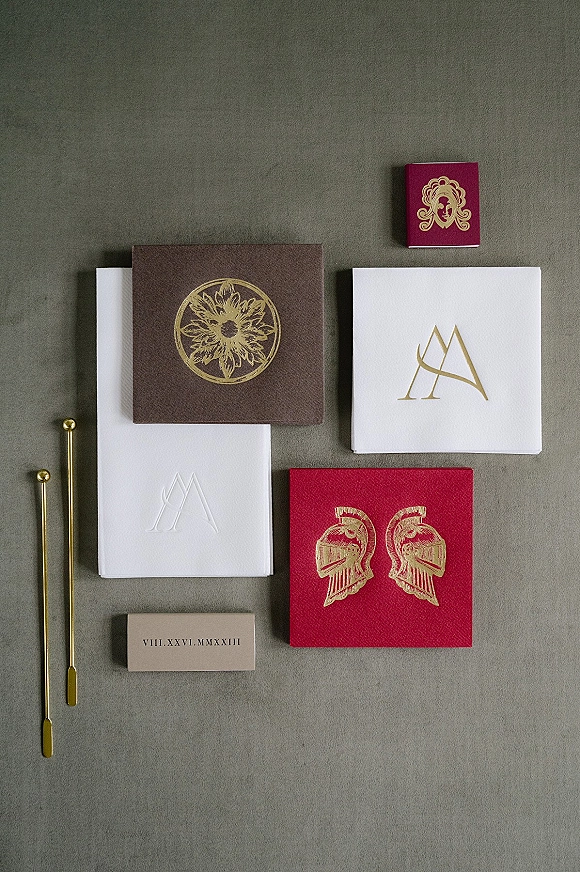Invitation suite with letterpress cards and monogram design, gold foil accents and wax seal tools on a gray fabric backdrop