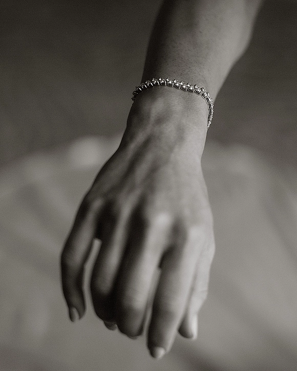 Bridal bracelet diamond tennis bracelet sparkling on a bride’s wrist, delicate diamonds catching light against a softly blurred indoor background