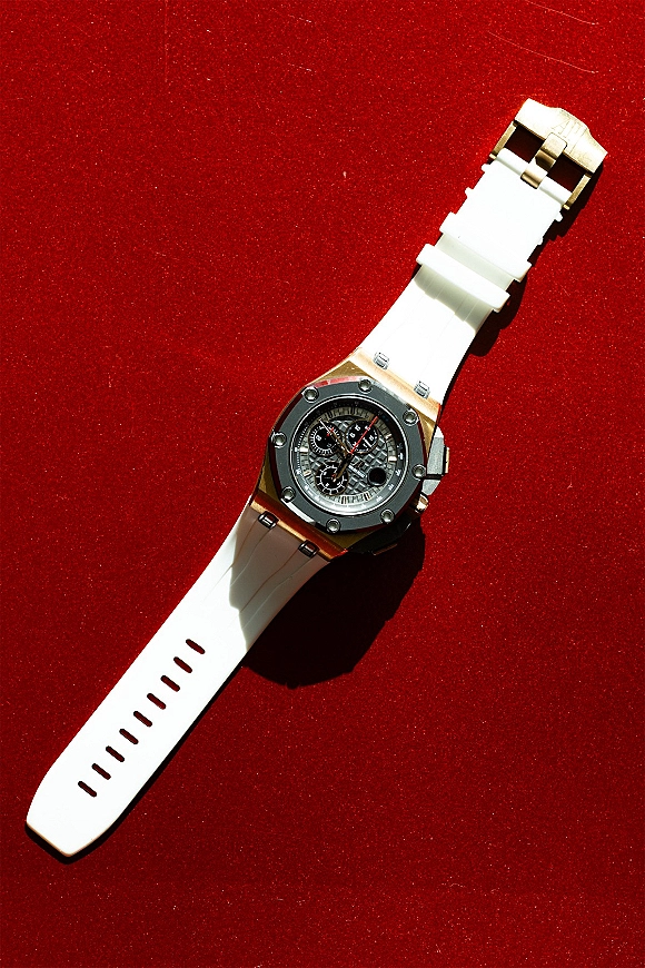 Groom watch with a white strap and chronograph face, metal case and buckle clasp displayed on rich red velvet fabric backdrop