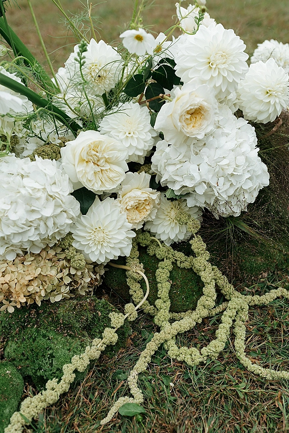 Wedding florals with white wedding flowers—dahlias, garden roses, hydrangea and greenery with trailing amaranthus on grass in a garden setting