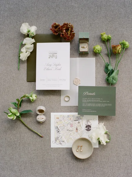 Invitation suite wedding invitation flat lay with green cards, envelopes, wax seal ribbon, rings and pearl earrings on linen backdrop