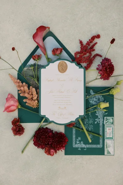 Wedding invitation suite featuring emerald wedding invitations and a classic wax seal, neatly arranged on a light textured surface.