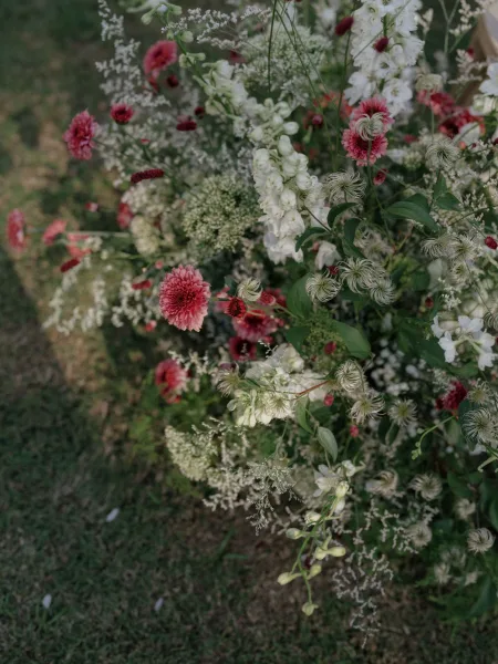 Wedding floral arrangement of pink and white wildflowers with lush greenery arranged on a grass lawn for an outdoor ceremony entrance