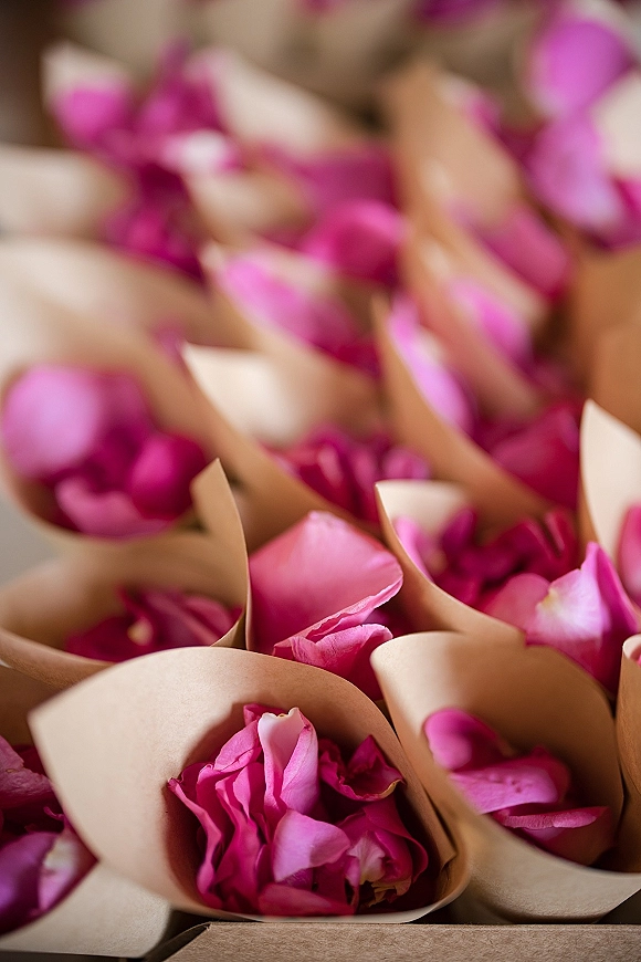 Flower petal cones for wedding petal toss filled with pink rose petals in kraft paper cones arranged on a tray tabletop