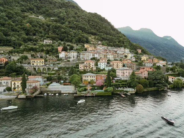 Wedding venue view of a lake wedding venue with waterfront terrace and dock, boats on the water, and pastel hillside village below mountains
