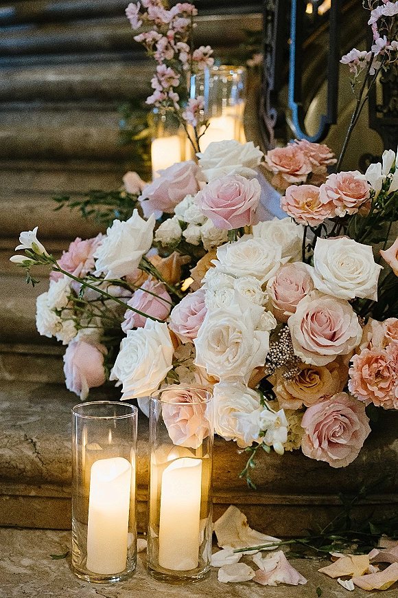 Wedding floral decor with staircase wedding flowers of pink, white, and peach roses with greenery, glass cylinder candles on stone stairs