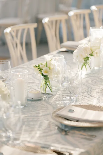 Reception tablescape featuring white wedding table decor highlighted by pillar candles, with elegantly arranged place settings throughout.
